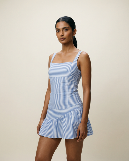 Woman wearing a blue striped corset nd skirt against a beige background